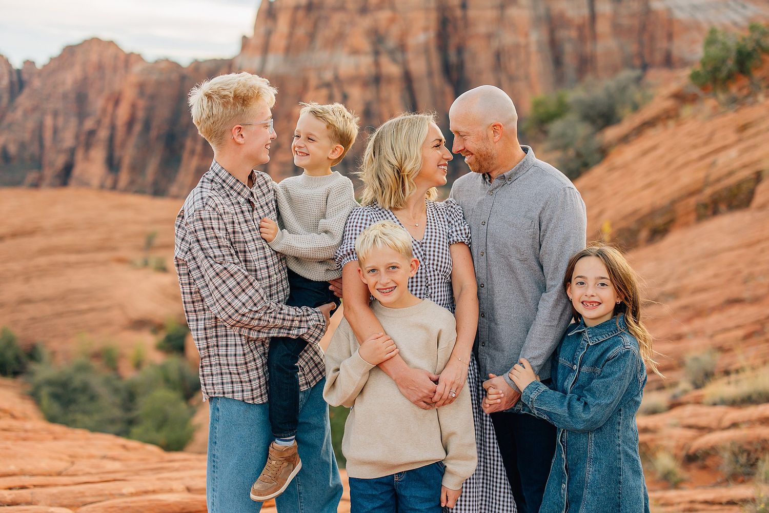 Family embracing and laughing together during desert photo session at sunset.