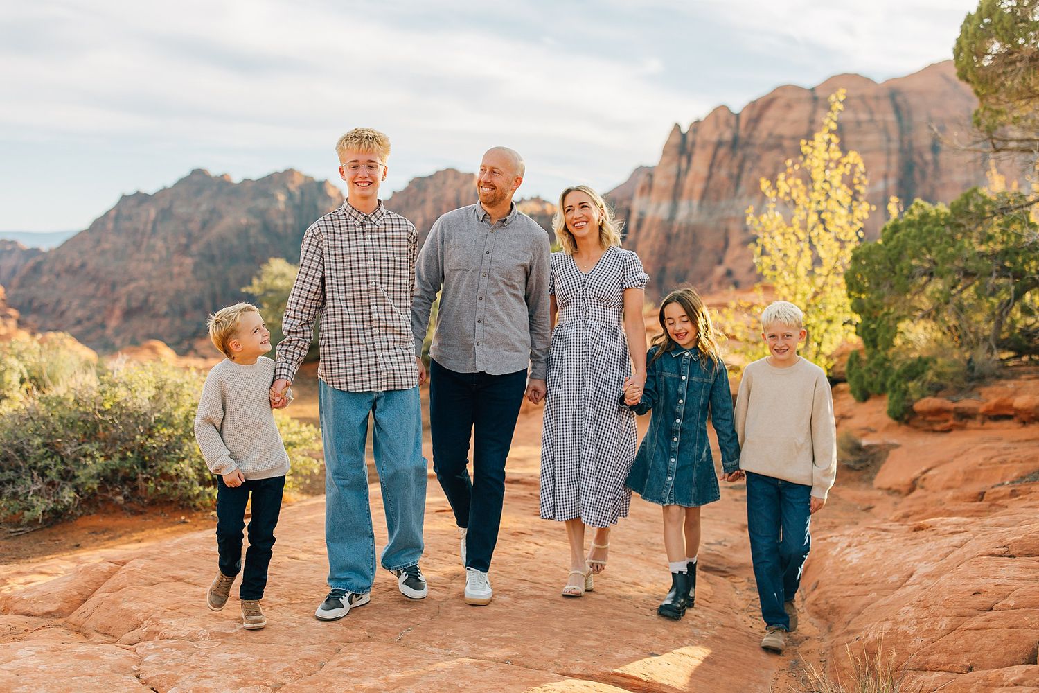 Family walking and playing together on red rock formations during sunset photo shoot.