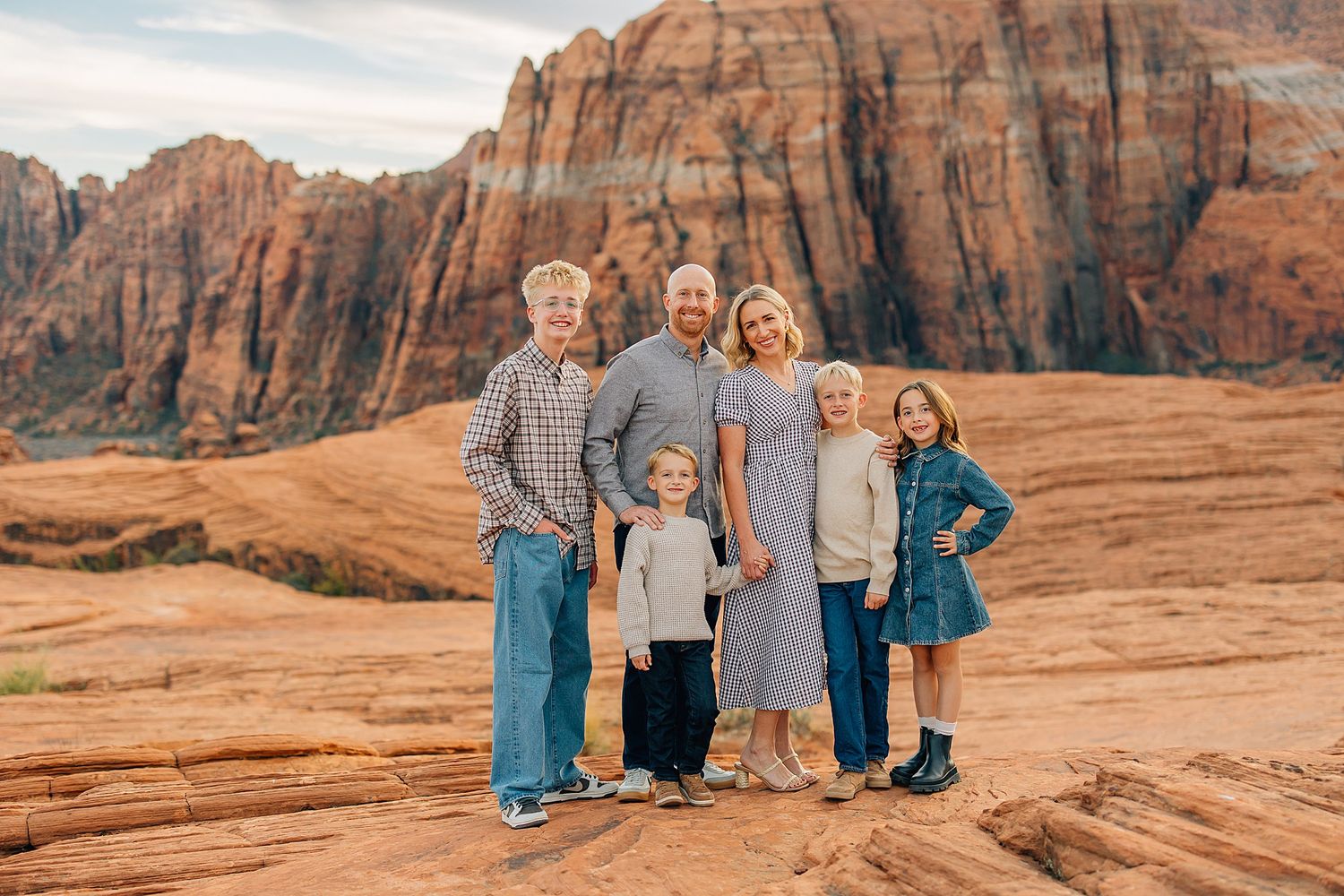 Multi-generational family group portrait with towering red rock cliffs as backdrop.