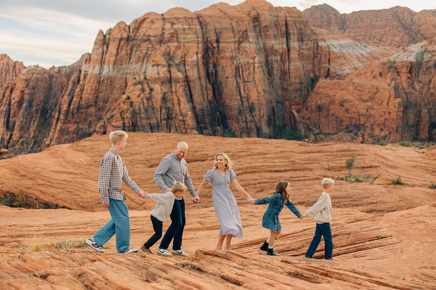 Candid family moments captured against majestic desert cliffs and blue sky.
