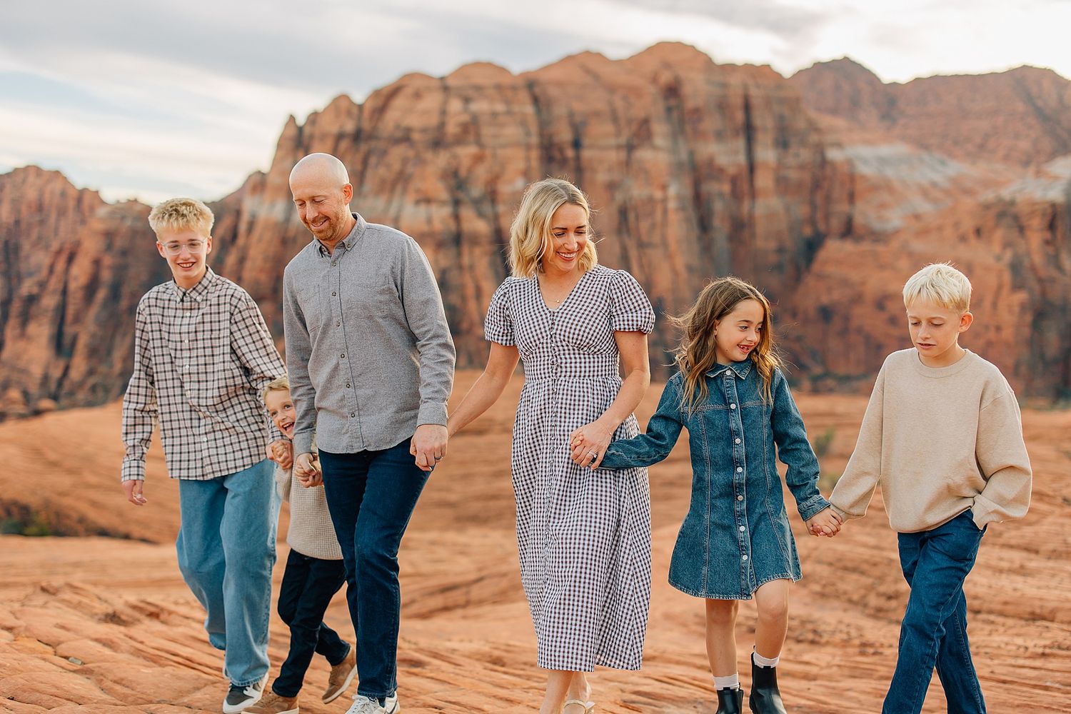 Natural family interactions on red rock formations during golden hour photography session.