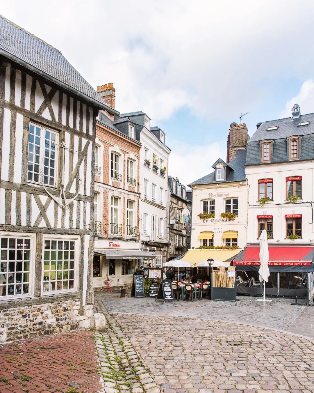 Historic timber-frame buildings overlooking a quiet cobbled square in a French town.