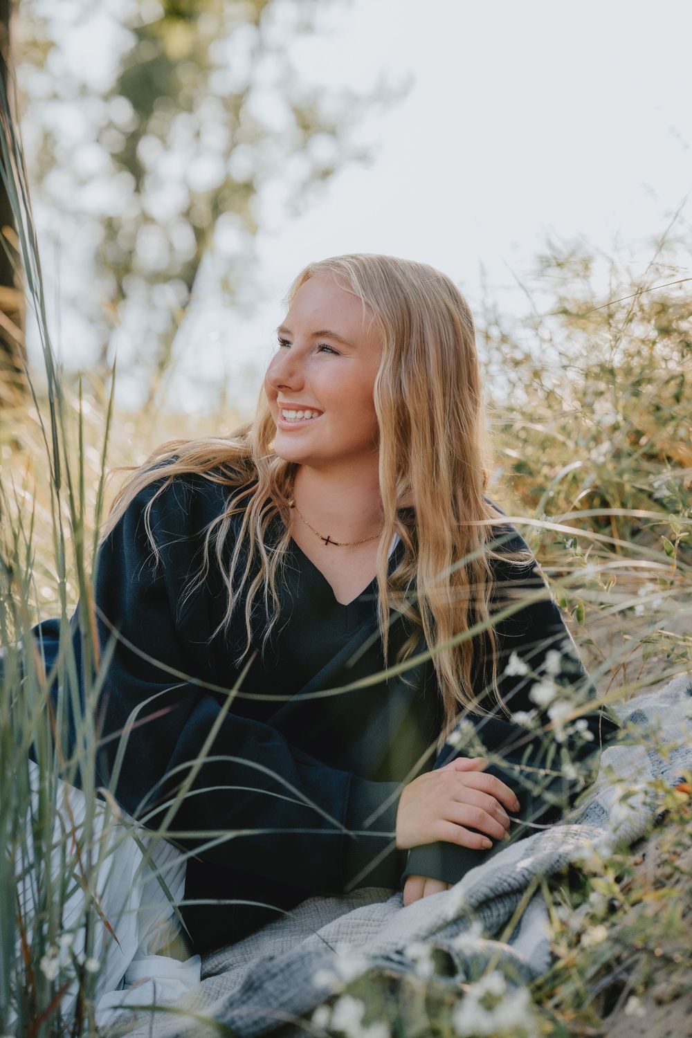 A series of outdoor portrait shots showing someone laying in tall grass and wildflowers at golden hour.