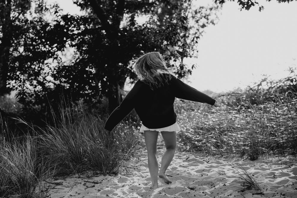 A sequence of black and white photos showing someone walking along a rocky coastal path through tall grass.