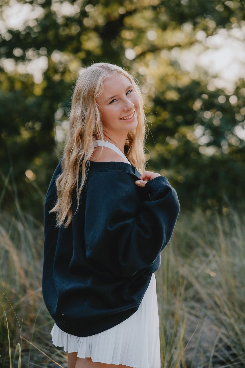 Outdoor lifestyle photoshoot in a natural setting with navy sweater and flowing white skirt.