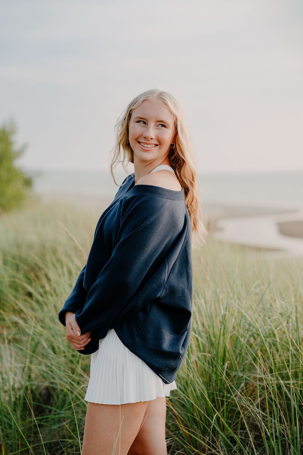 Candid poses among tall beach grass wearing casual navy and white outfit.