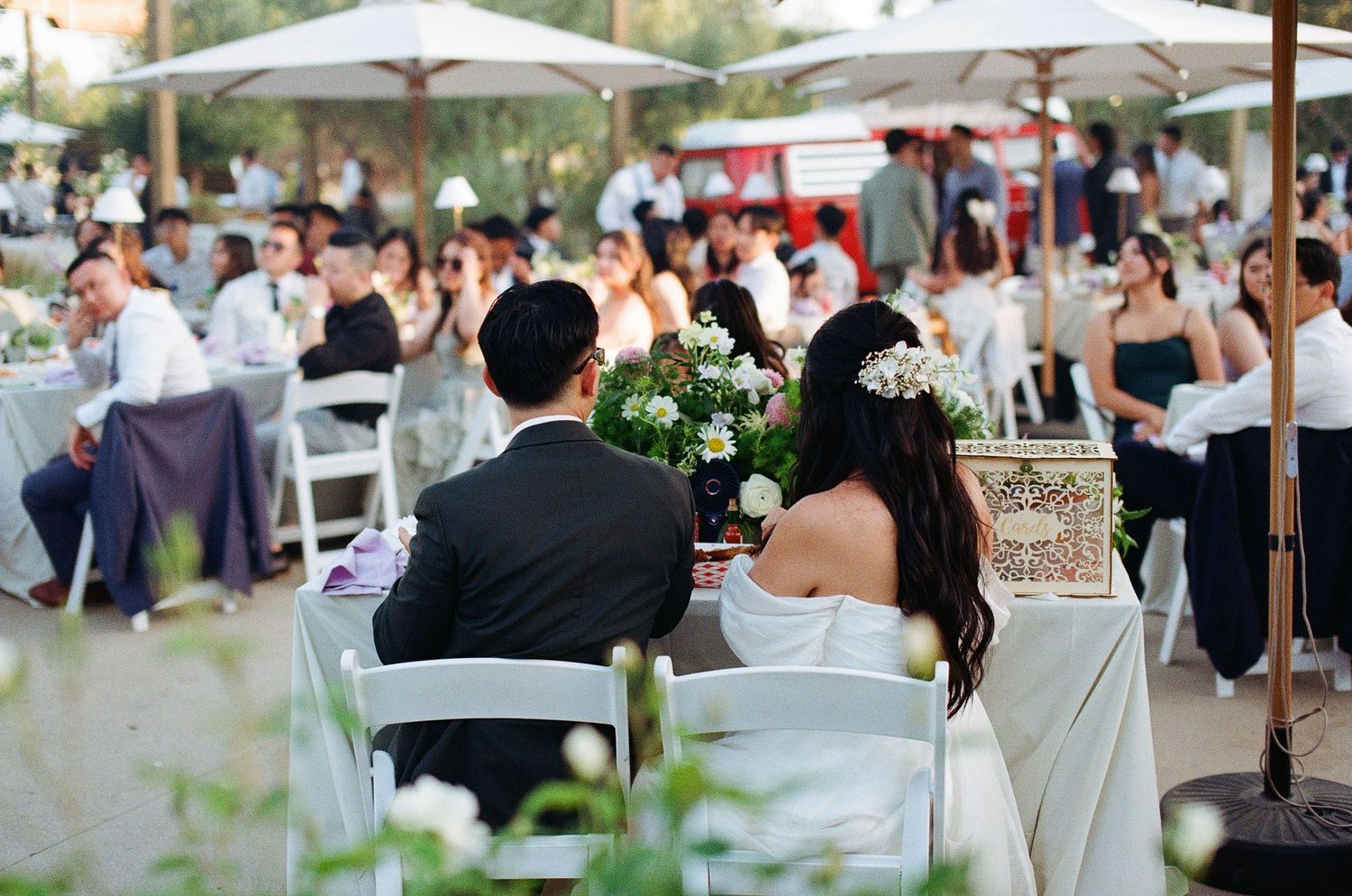 A quiet 35mm film photo of the bride and groom watching their wedding ceremony guests from a distance.