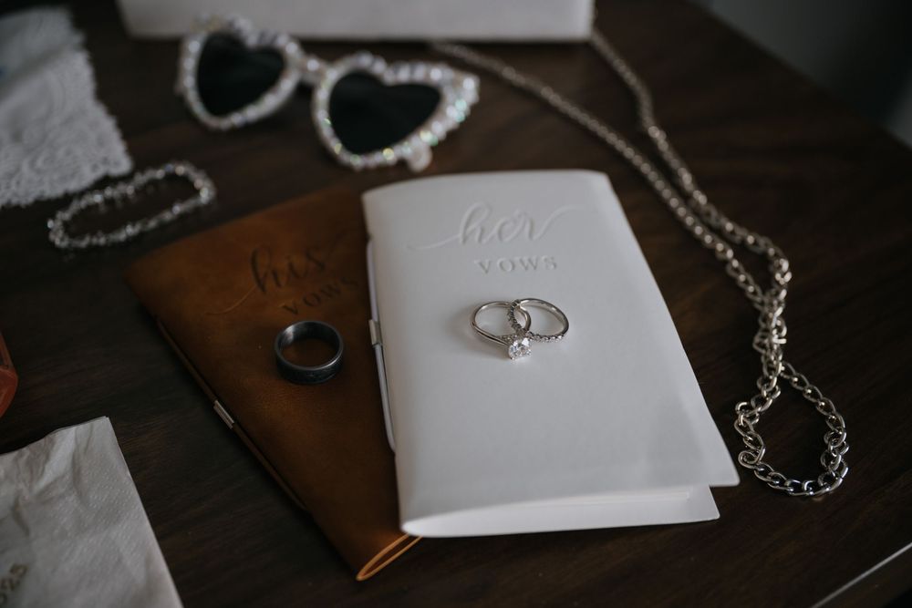 A collection of jewelry pieces including rings and necklaces arranged on white paper against a dark wooden surface.