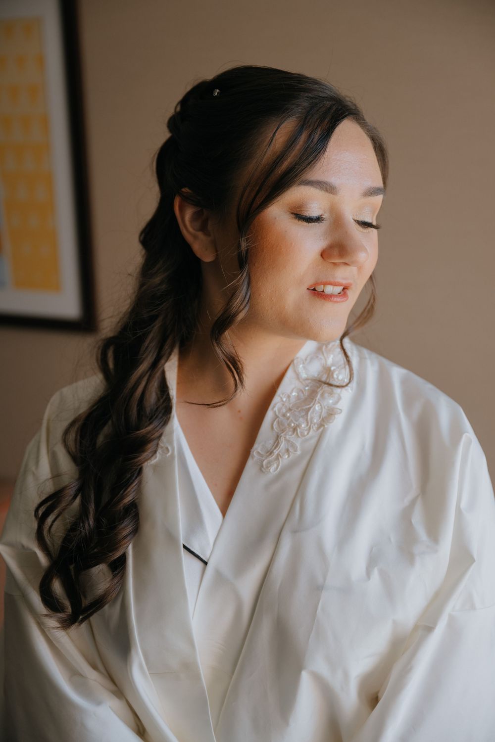 A woman in a white silk robe smiles while getting ready, shown in a series of soft, warm-toned photographs.