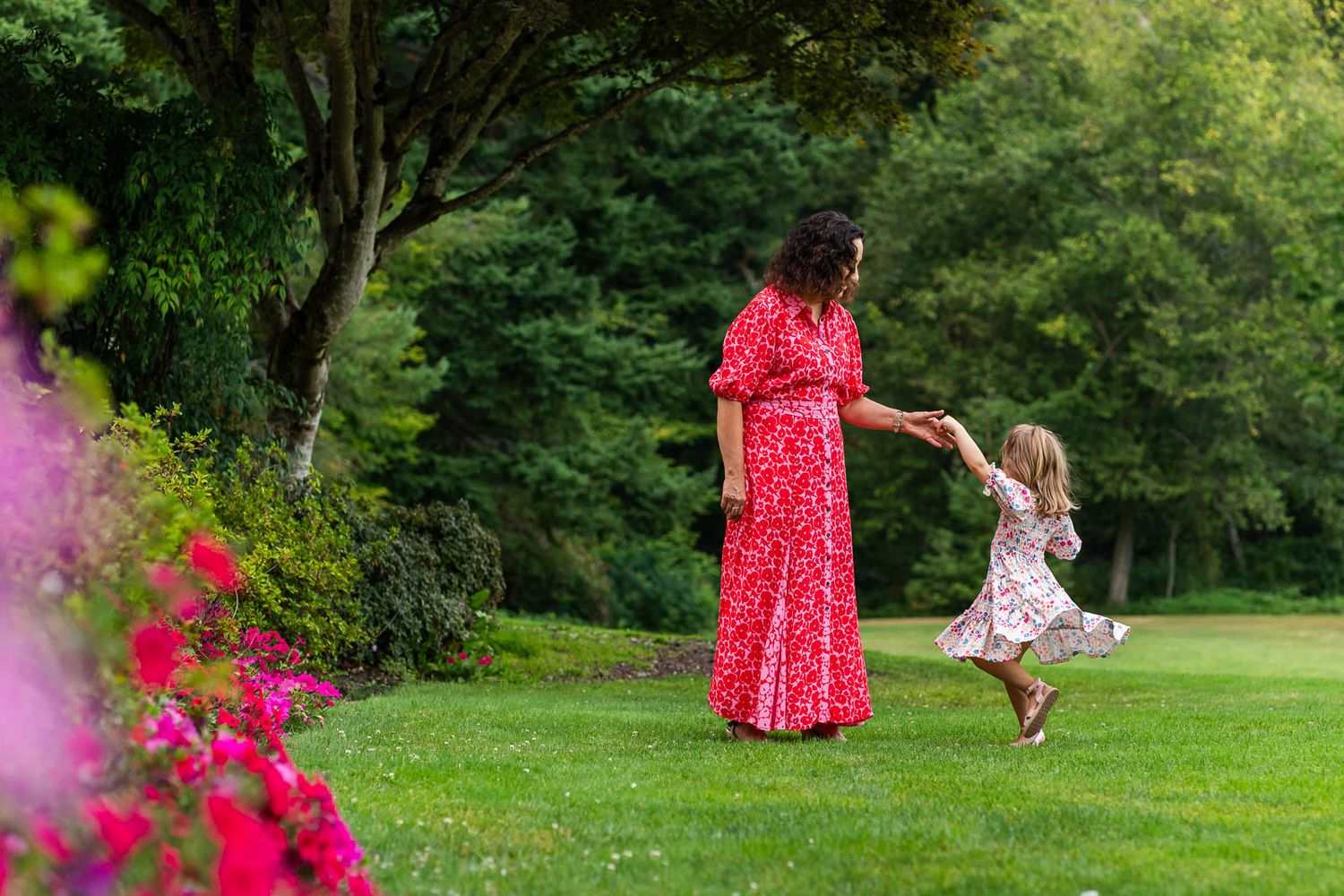 Grandma twirling her granddaughter in the garden.