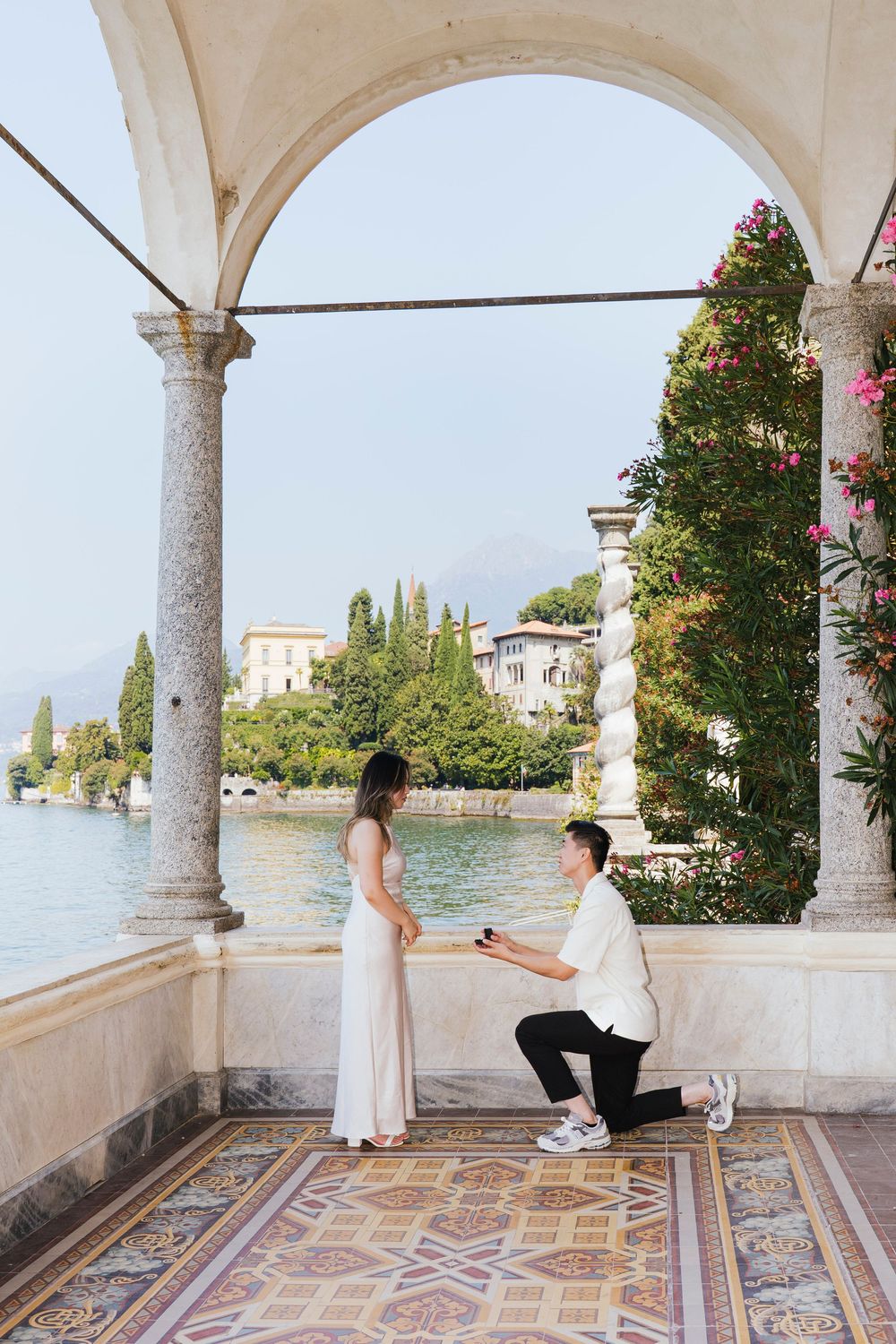 A romantic proposal sequence unfolds on an ornate lakeside terrace with white columns and patterned tile floor.