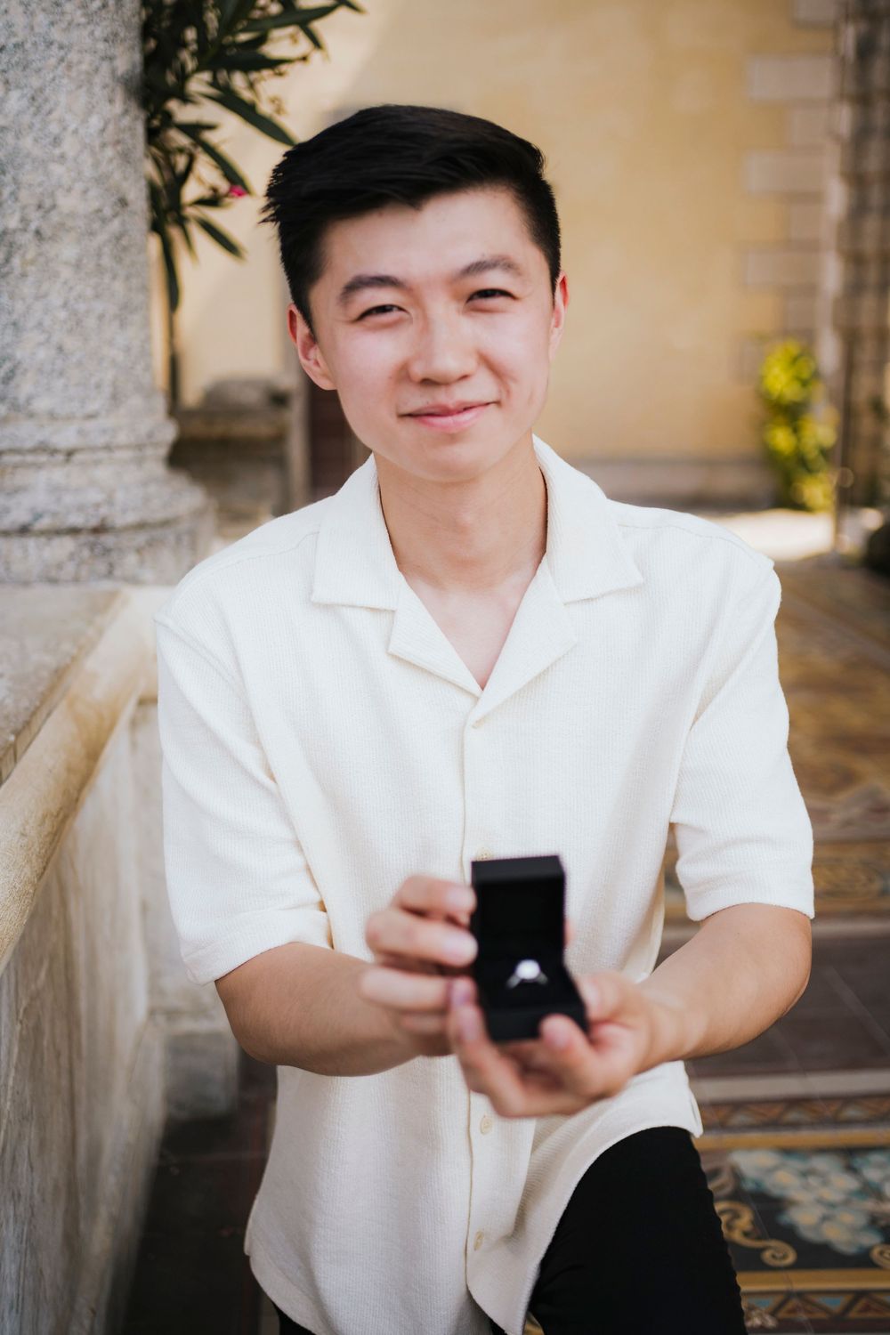 A sequence of photos showing someone in a white shirt holding and opening a small black box.