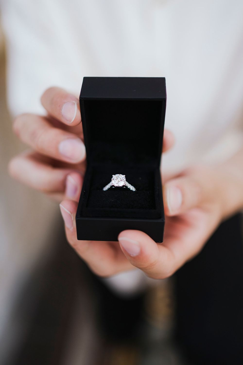 Close-up shots of hands holding a black ring box revealing an engagement ring inside.