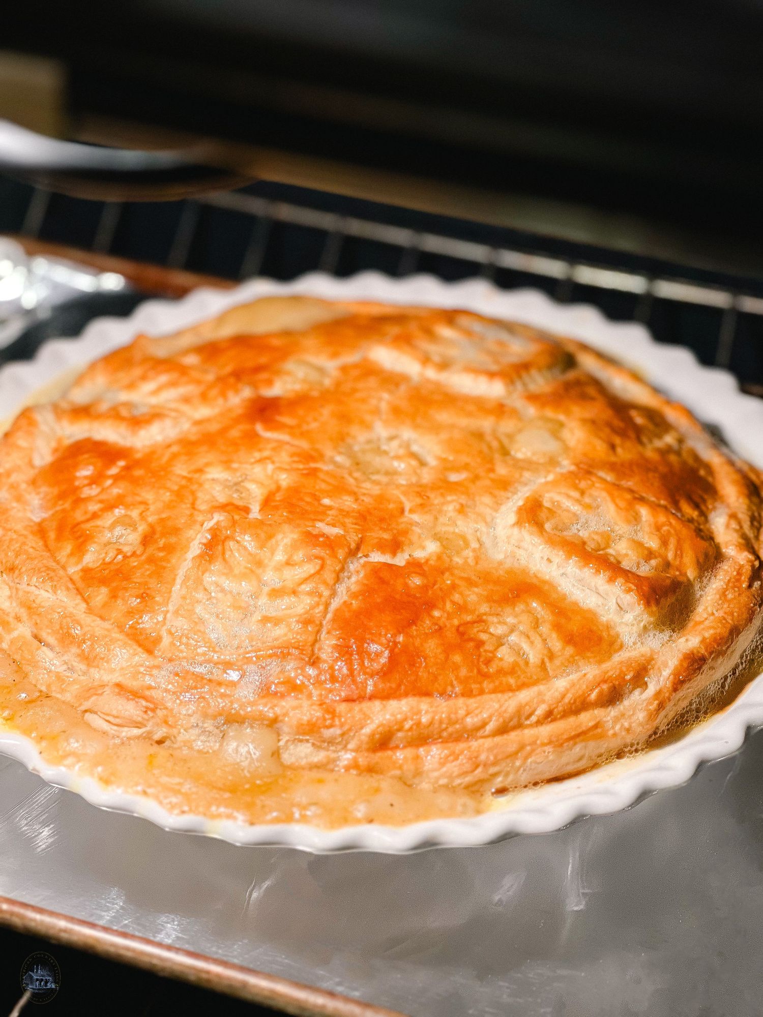 Golden brown pie crust baking in the oven with a flaky top.