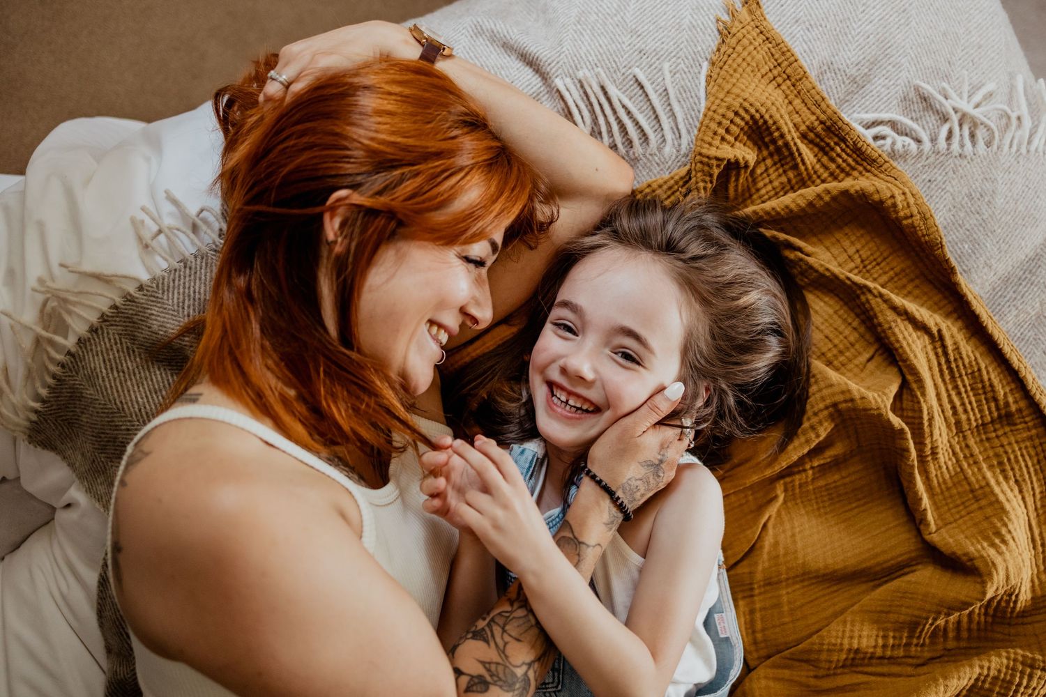 Family sharing intimate moment on patterned rug in soft indoor lighting.