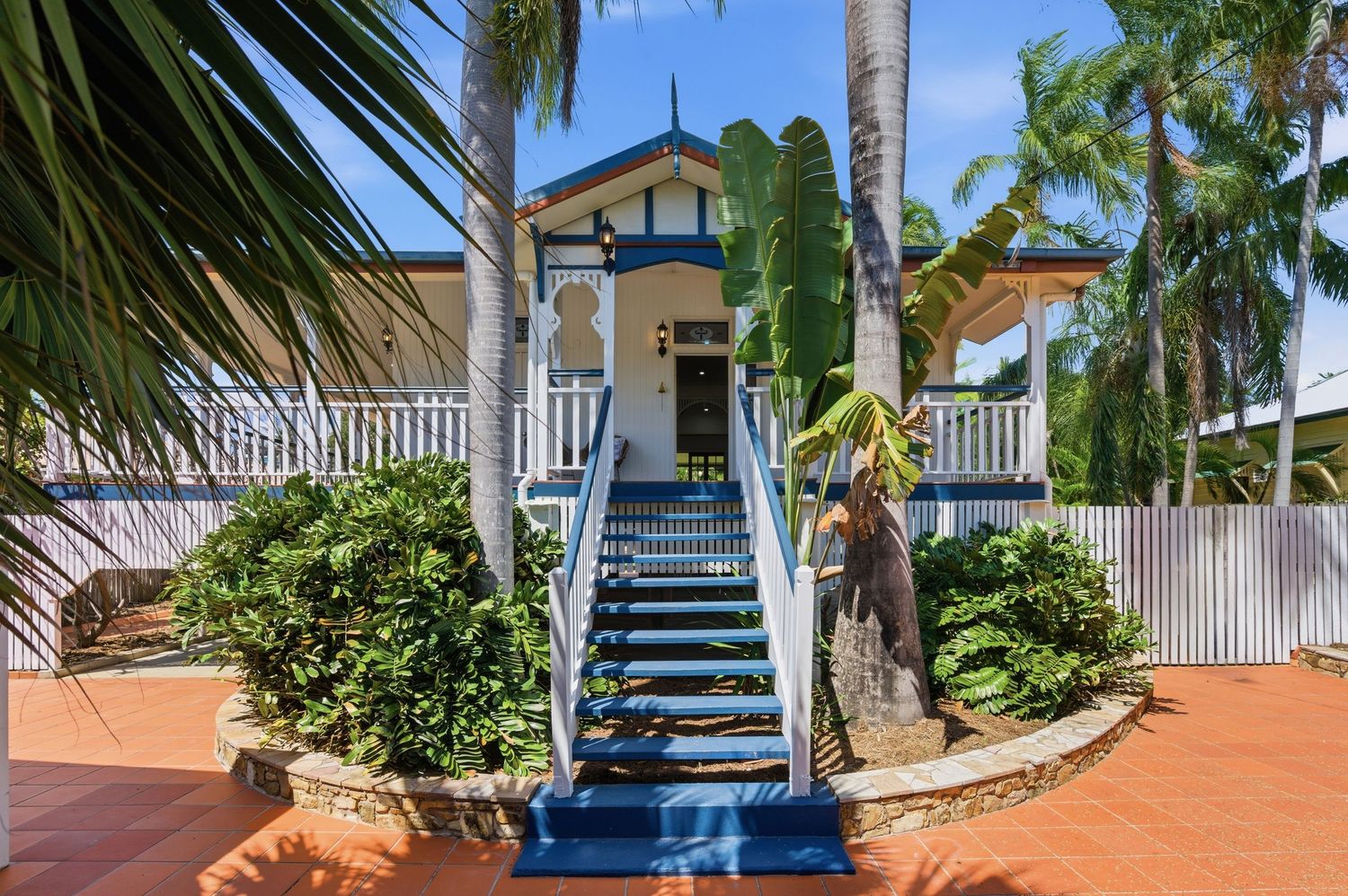 Modern residential driveways with palm trees and white exterior finishes in a tropical setting.