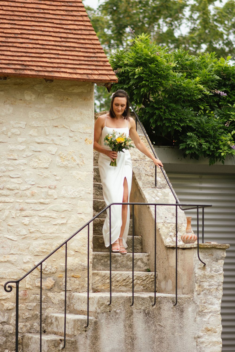 La mariée descend les marches d’un vieux bâtiment en pierre typique de Sologne, à La Ferté-Saint-Aubin.
