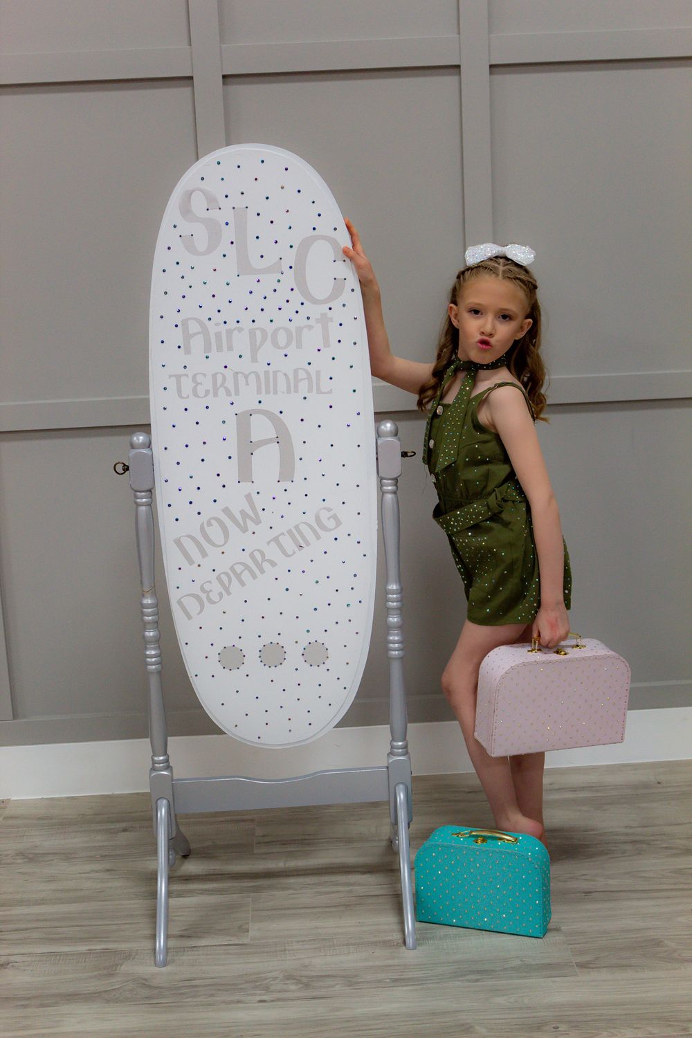 Playful poses with a decorative white chair and colorful props on light wooden flooring.