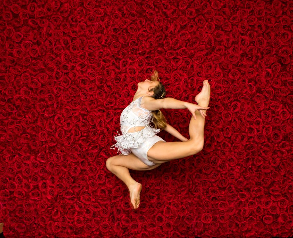 Dynamic dance poses captured against a deep red textured background on wooden flooring.