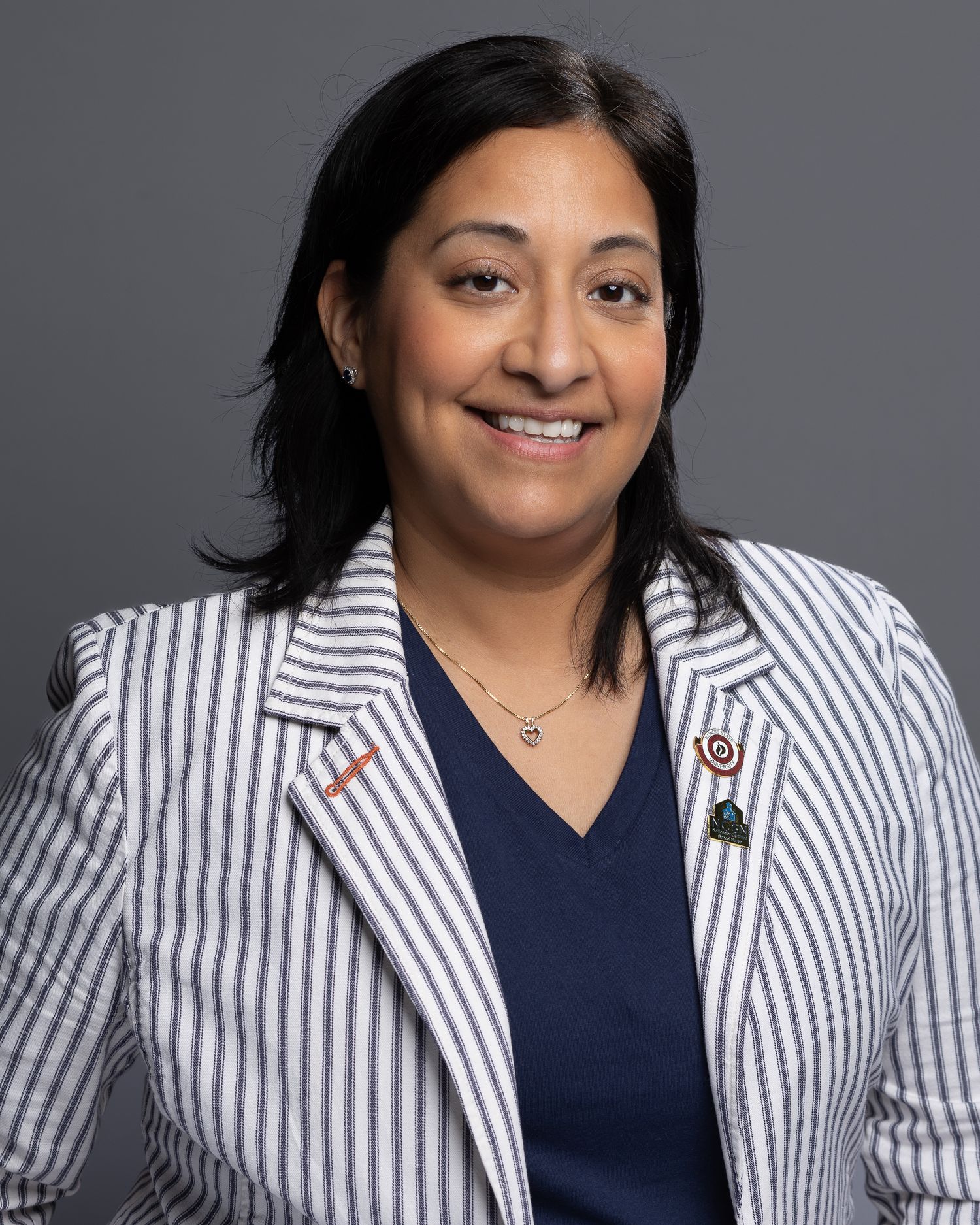 Professional headshot series showing person in navy blouse and white striped blazer against gray background.