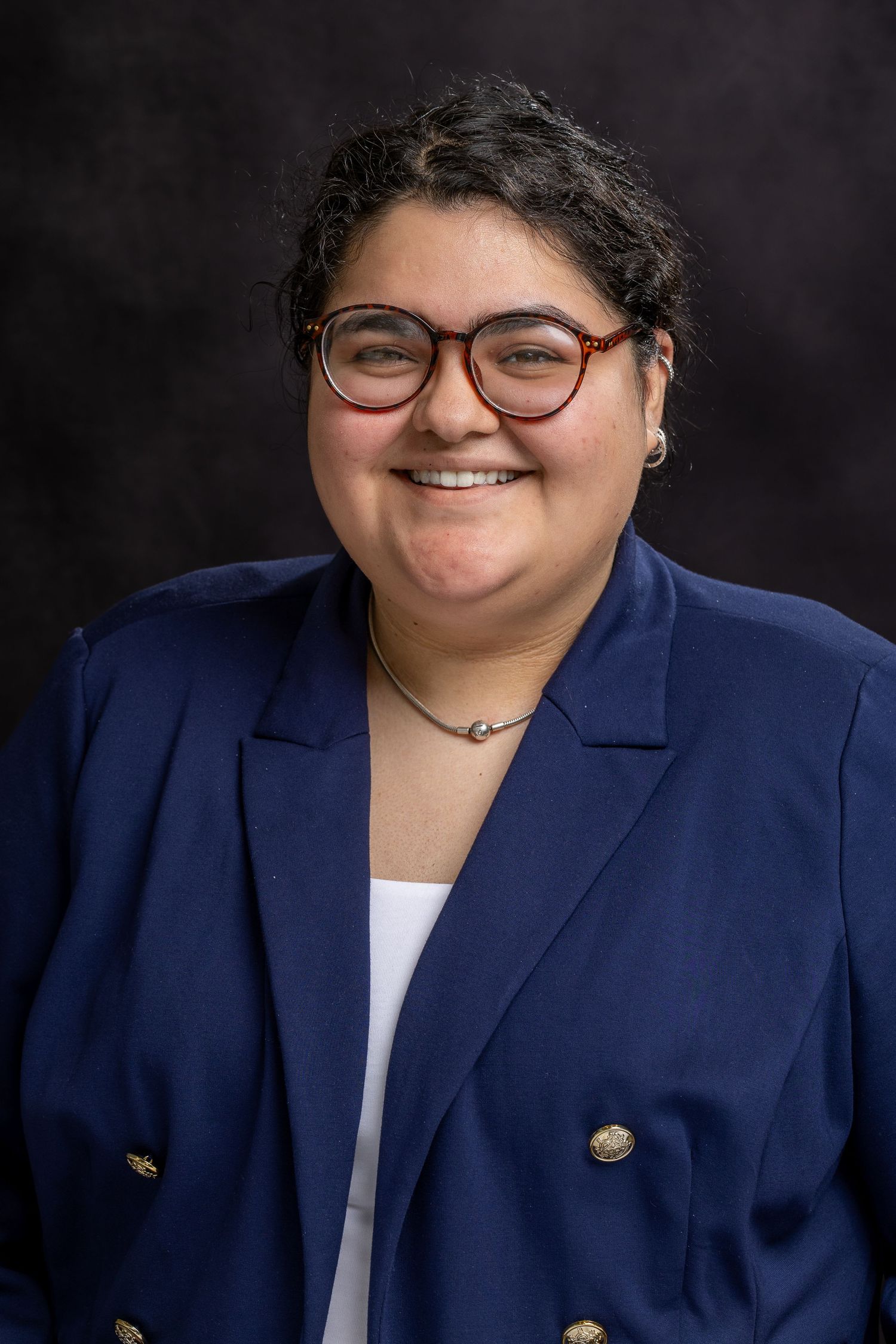 Professional headshot series showing a person in a navy blazer and white top against a dark background.
