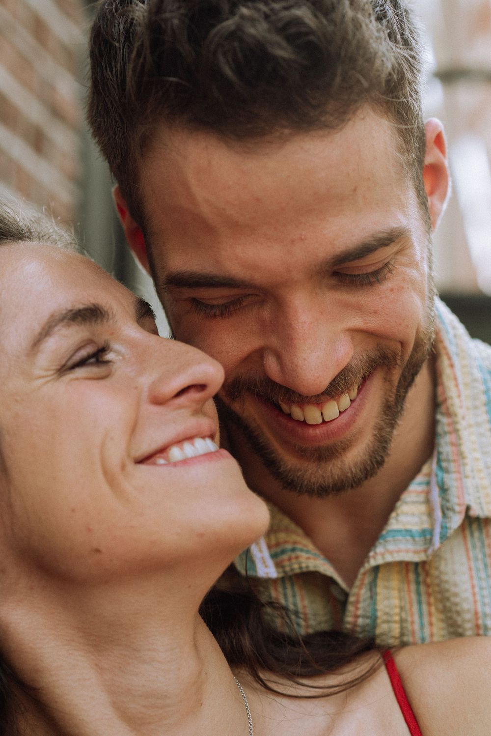 Close-up candid shot of couple sharing tender moment outdoors.