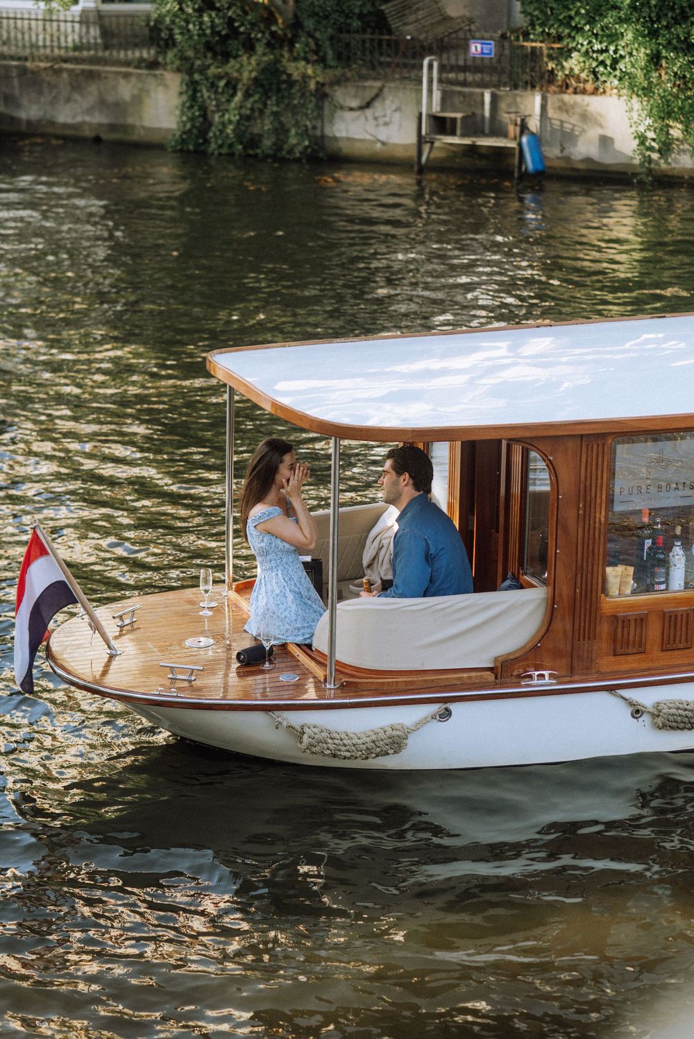 Elegant wooden pleasure boat cruising along a canal with passengers aboard.