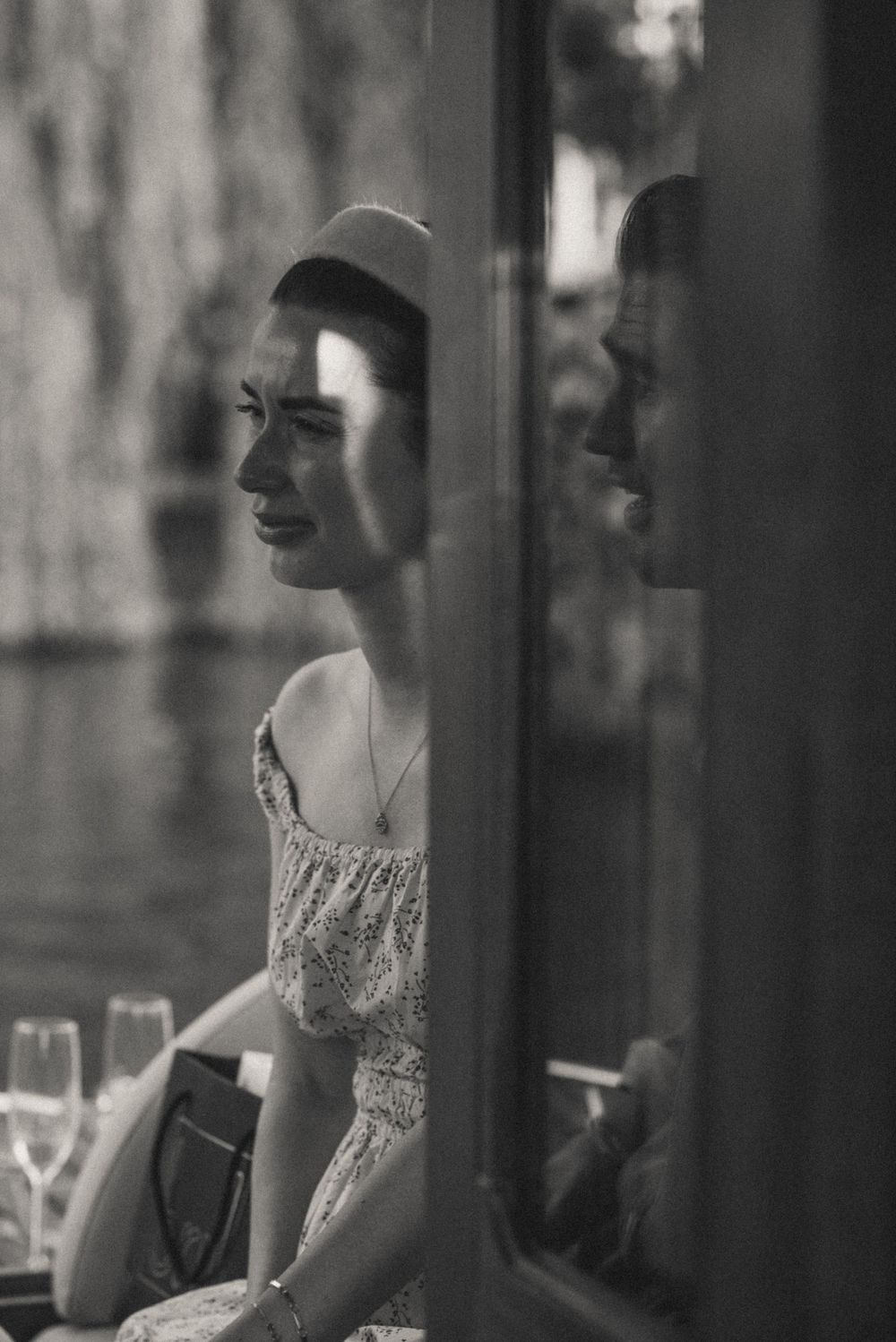Black and white artistic portrait showing vintage glamour through window reflections.