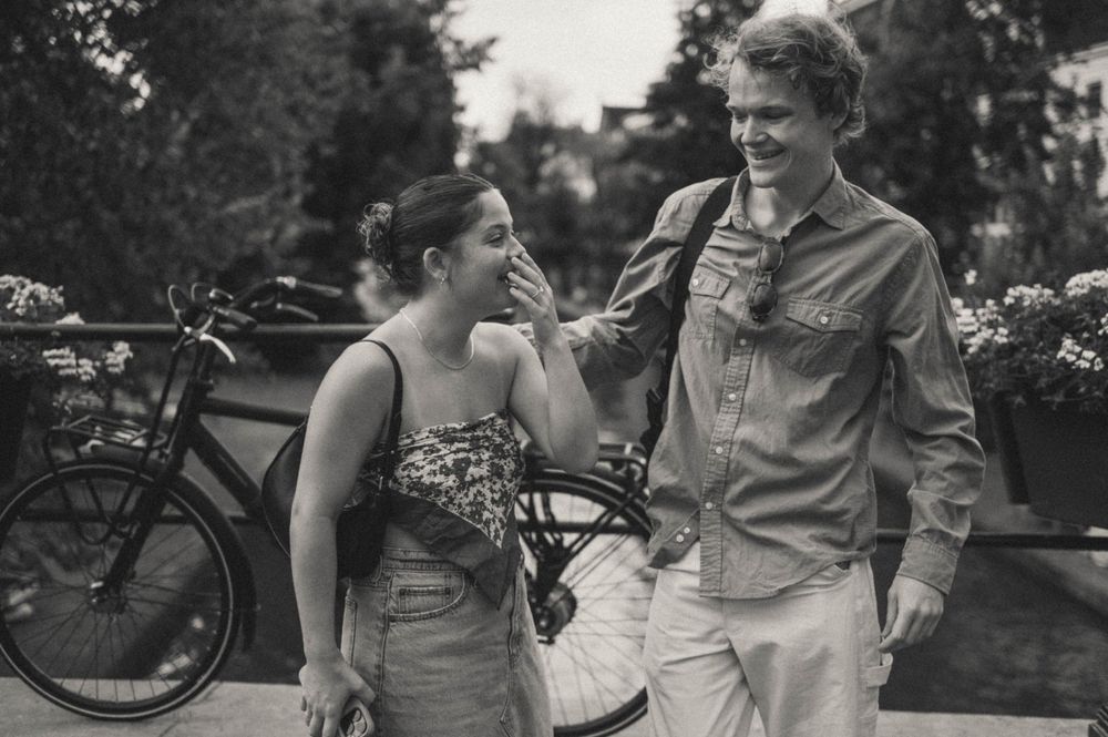 Candid black and white photo of couple sharing intimate moment outdoors.