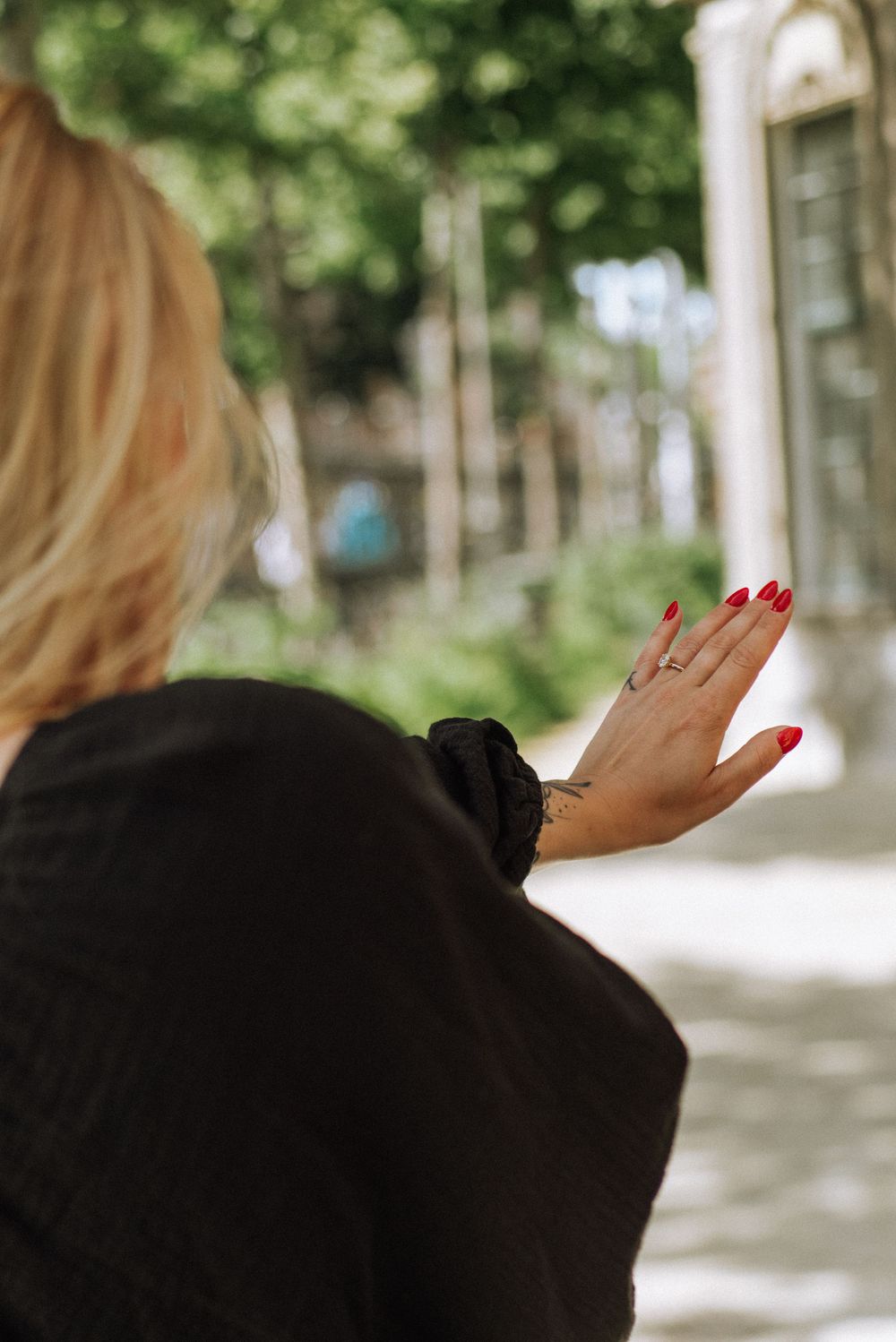 Close-up shot showing hands with red nail polish against a soft focus natural background.