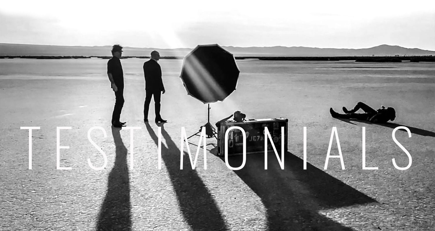 black and white bts photo Mark Maryanovich lying on ground while photographing 7Horse standing in desert guitar and case