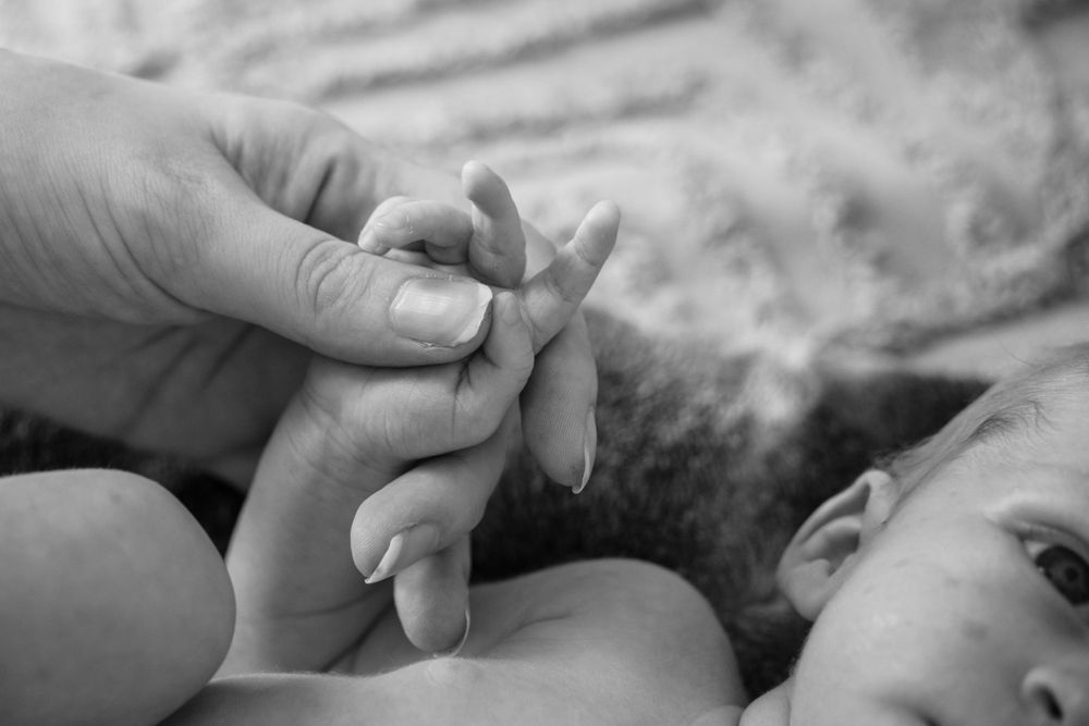 mother holding newborns hand