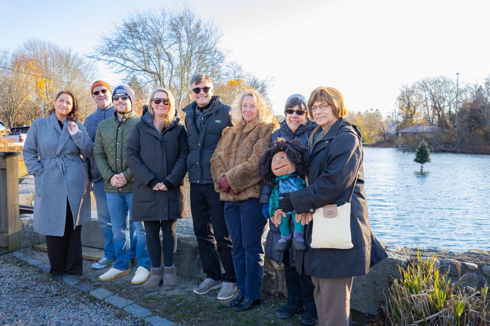 Group of visitors gathered by a waterfront on a winter afternoon.