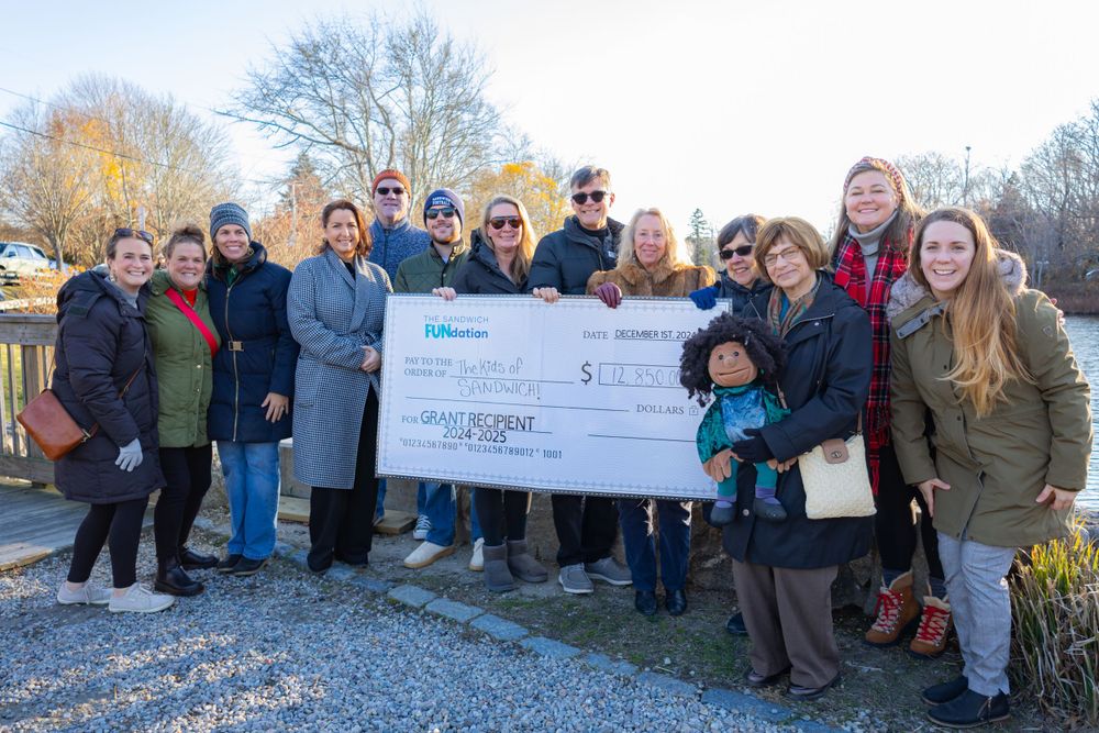 Group photo of community members holding a large presentation check outdoors.