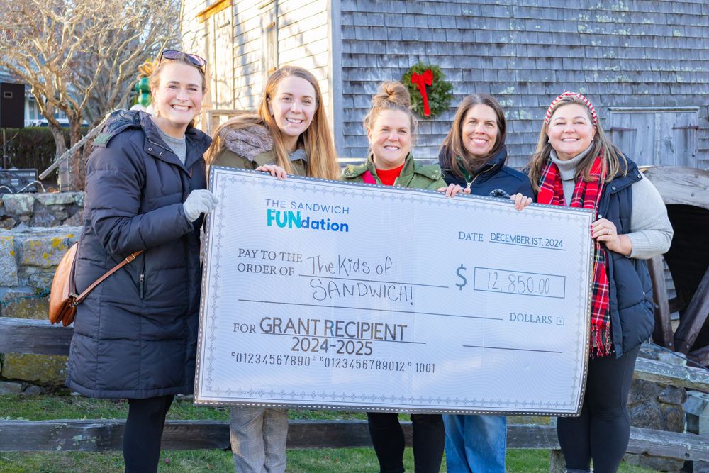 Group displaying an oversized check from FMGlobal outdoors on a winter day.