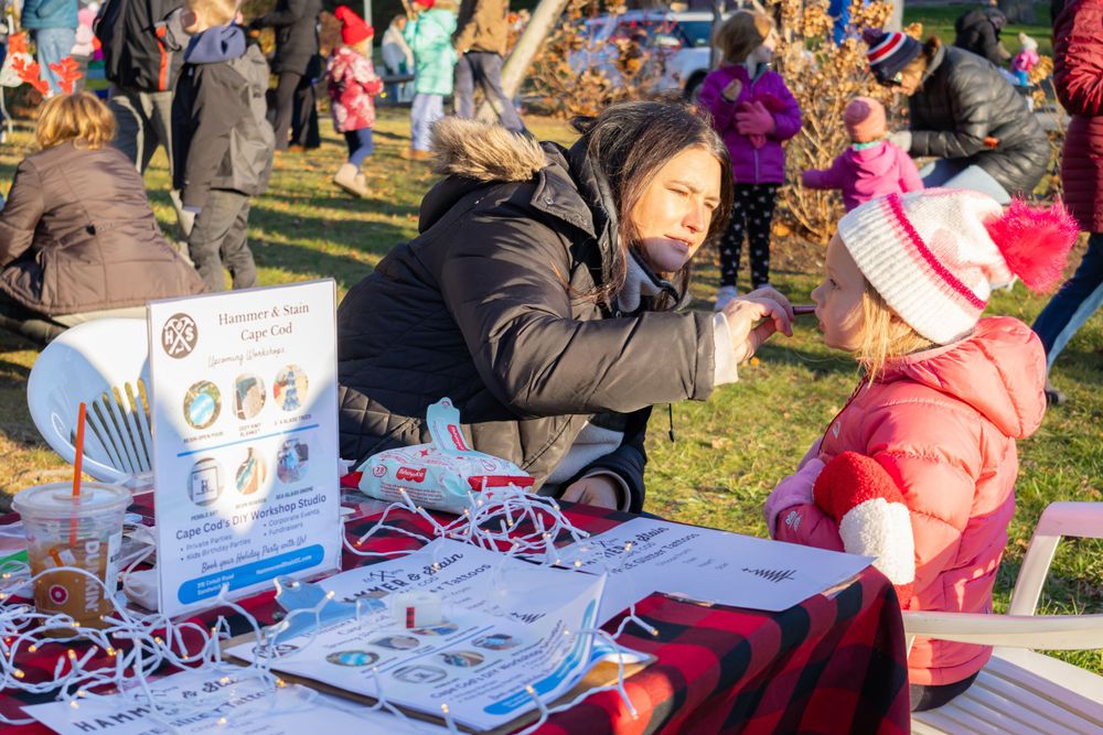 Holiday craft fair vendor displays merchandise on sunny winter day.