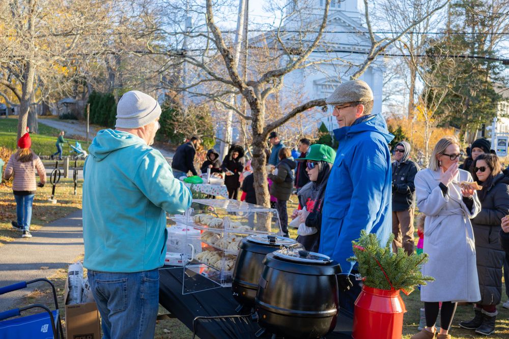 Community gathering with winter food service in a park setting showing cooking stations and attendees.