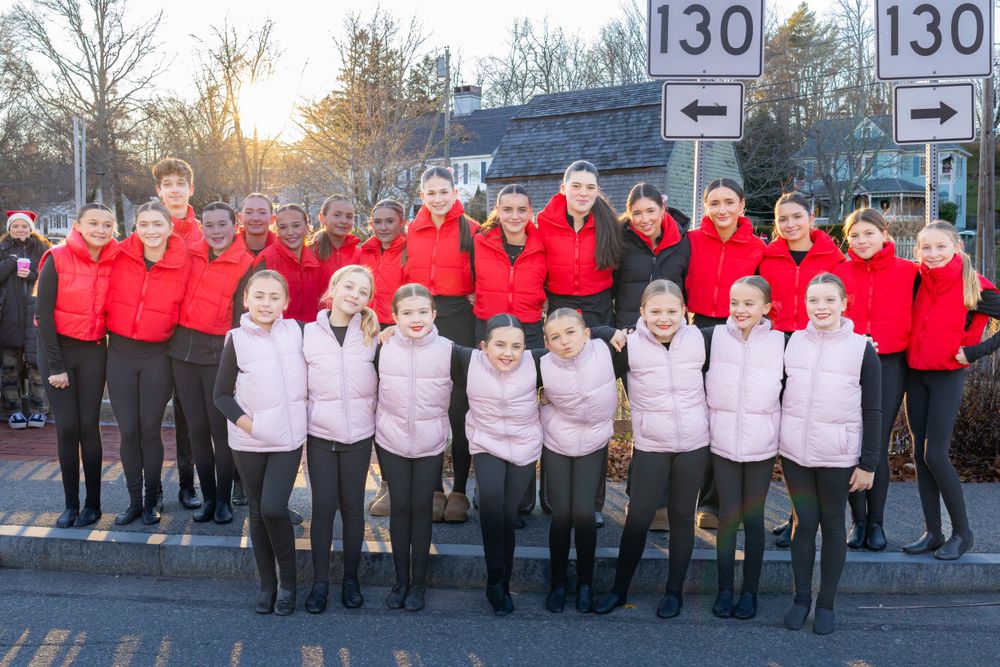 Group photo of a choir in matching red and white winter outfits at sunset.