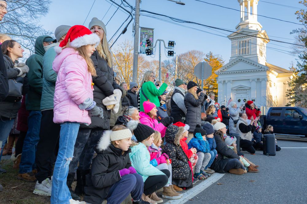 Crowd of spectators bundled up in winter clothes watching a holiday parade.