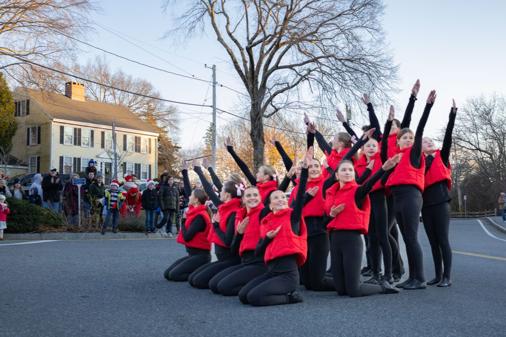 Performance group in red costumes striking a dramatic pose during an outdoor show.