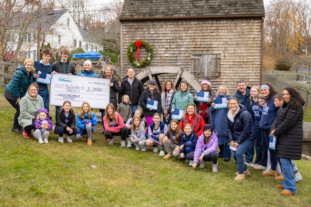 A large group gathered outside a rustic building with winter wreaths for a community event.