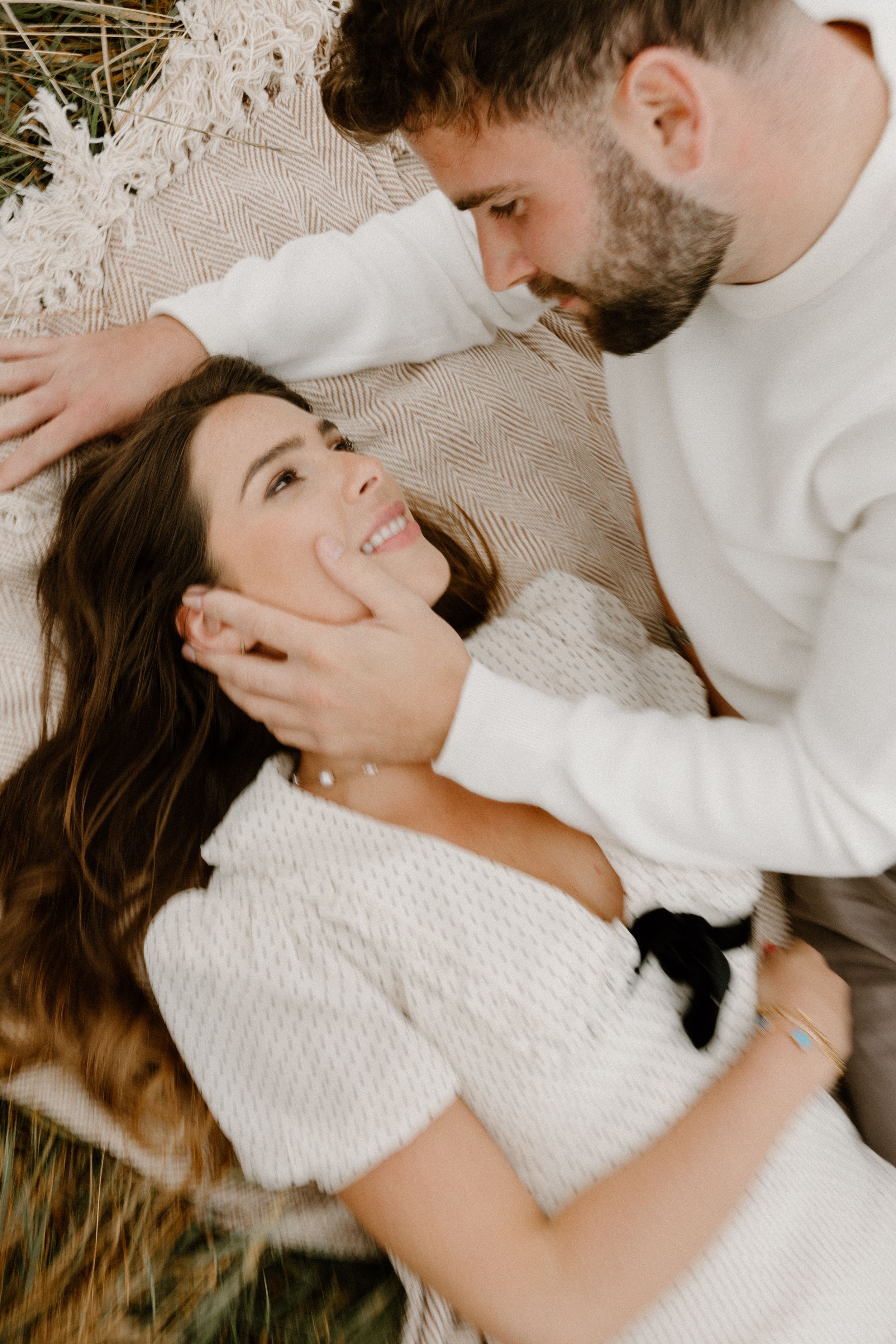 Romantic couple sharing an intimate moment while lying on a cozy blanket.