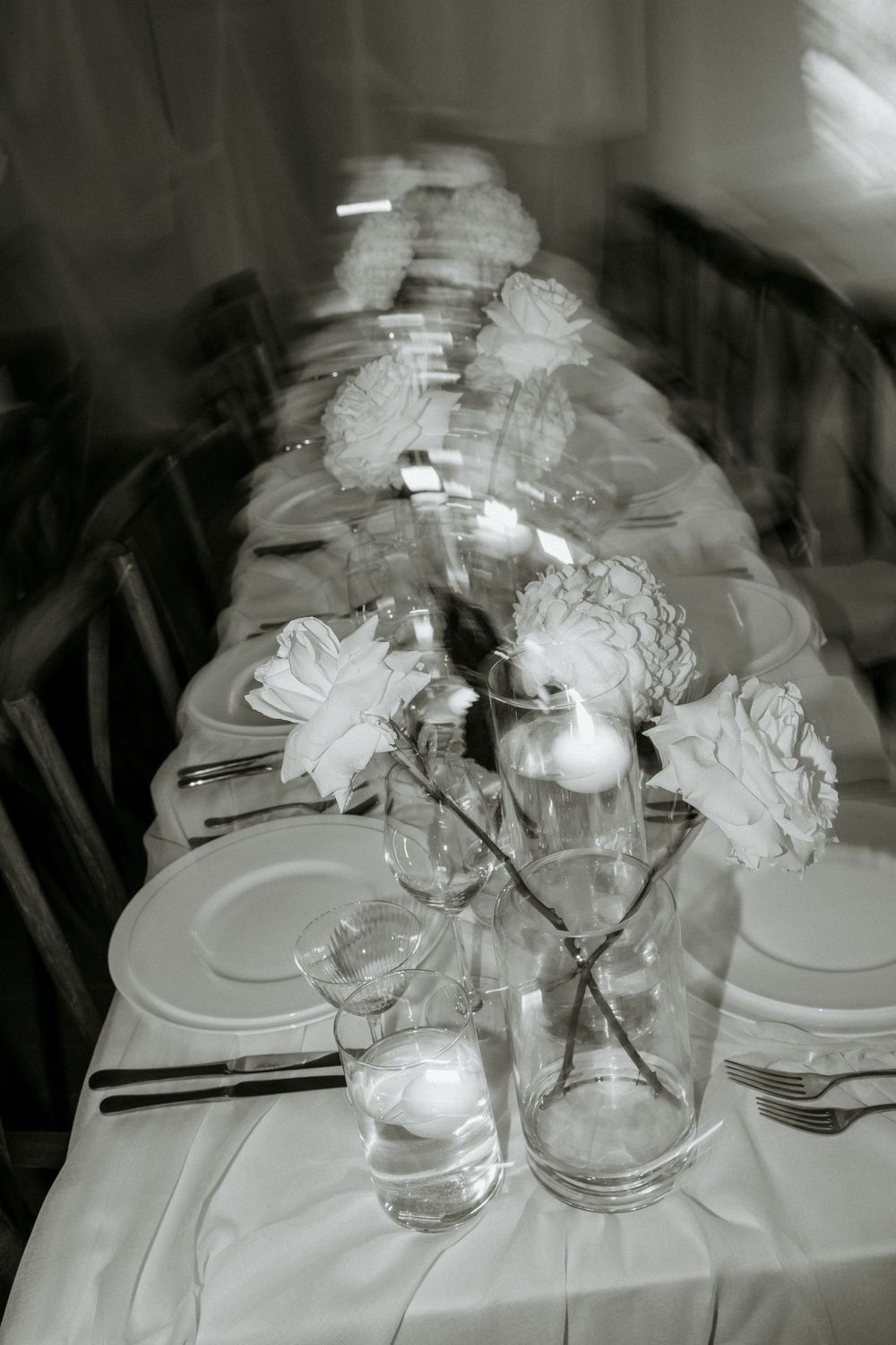 Black and white photo of an elegant table setting with floral centerpieces and place settings.