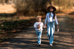Kids explore and play together on a dirt path surrounded by golden autumn foliage.