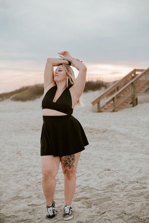 A series of beachside photos showing a figure in a black dress posing gracefully against sandy dunes and wooden boardwalks.