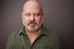 Headshot of Broadway actor Eric Leviton in a green shirt.