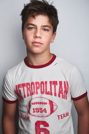 Headshot of a teenage boy in a graphic sports t-shirt and tousled hair.