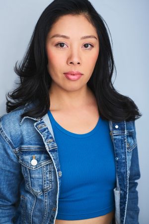 Headshot of a woman in a blue tank top and denim jacket.