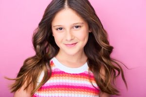 Headshot of actor Annie Braverman against a pink background.