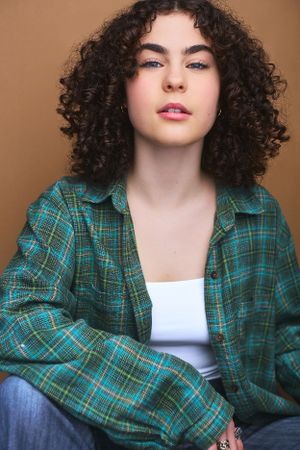 Headshot of a teenage girl in a green flannel shirt and short curly hair.